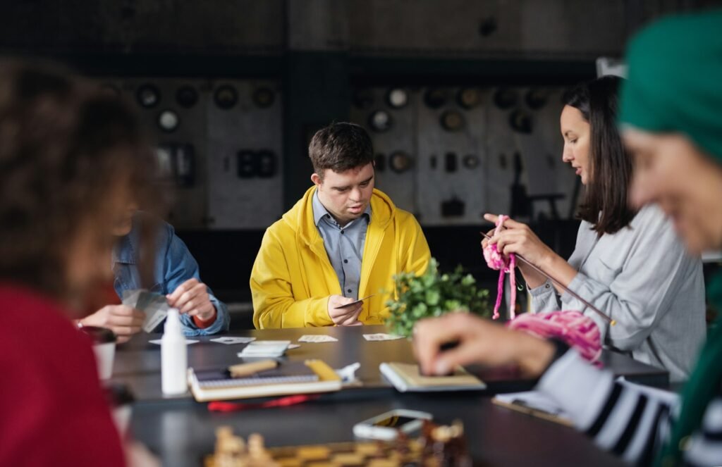 Group of people playing cards and board games in community center, inclusivity of disabled person